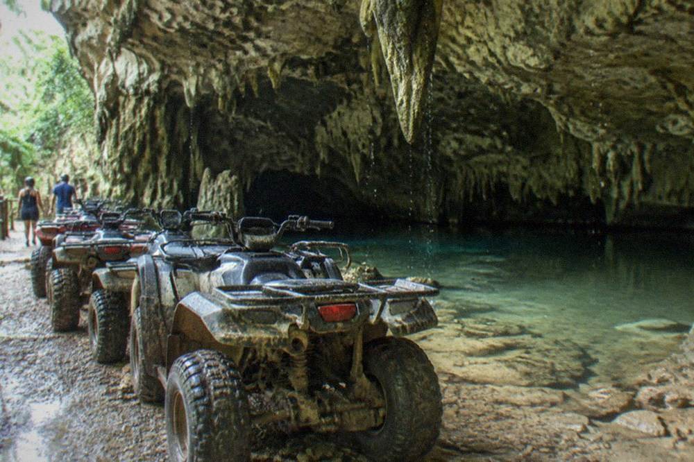 A group of ATVs parked near the entrance of a freshwater cave