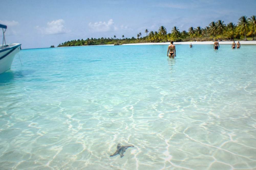 A calm turquoise natural pool sandbar near Saona Island with shallow clear water under a wide sky.