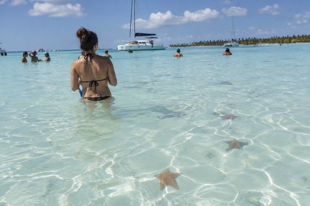 Waist-deep turquoise water over a sandbar with starfish near Isla Saona