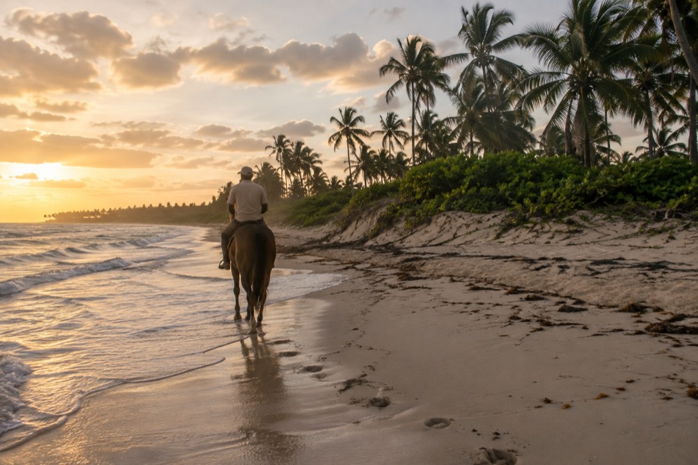 Horse and rider walking along the tide line at Uvero Alto beach