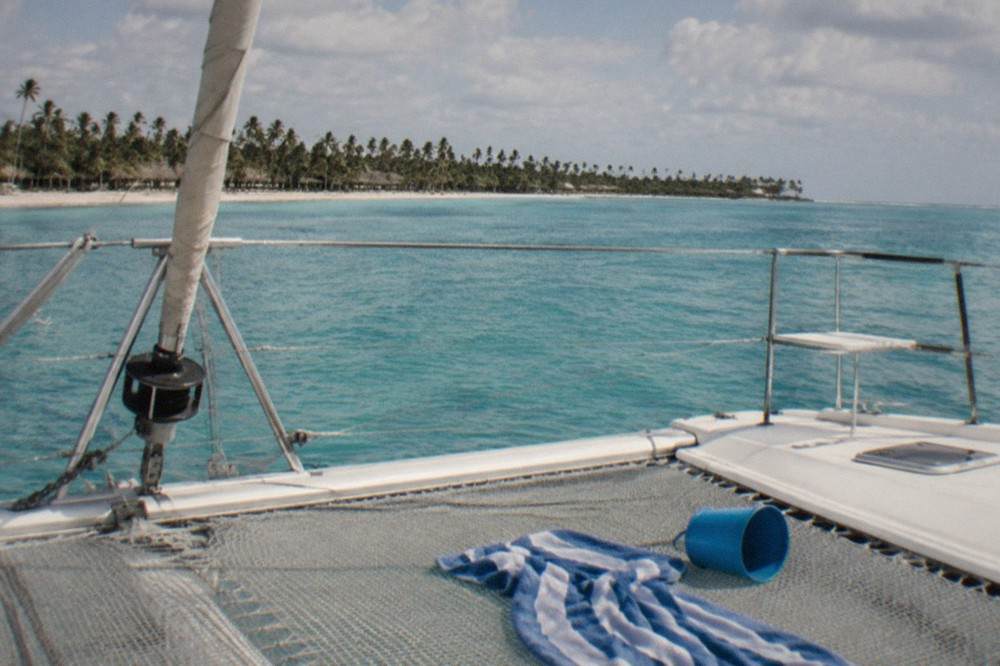 Empty catamaran deck with rigging and open turquoise sea beyond the railing