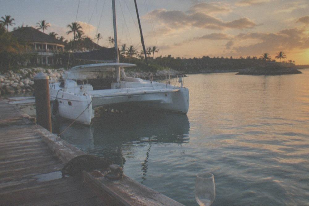 Resort dock at golden hour with a moored catamaran and calm sea