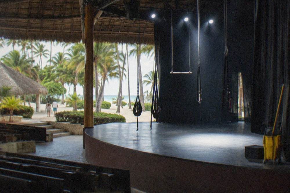 Raised nightclub stage with bright spotlights and trapeze rigging above an empty floor