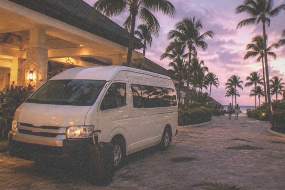 Shuttle van waiting on a resort driveway at dusk with palm trees