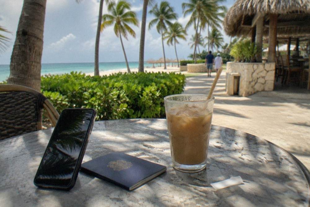 Phone displaying a QR code beside a passport and coffee cup on a cafe table