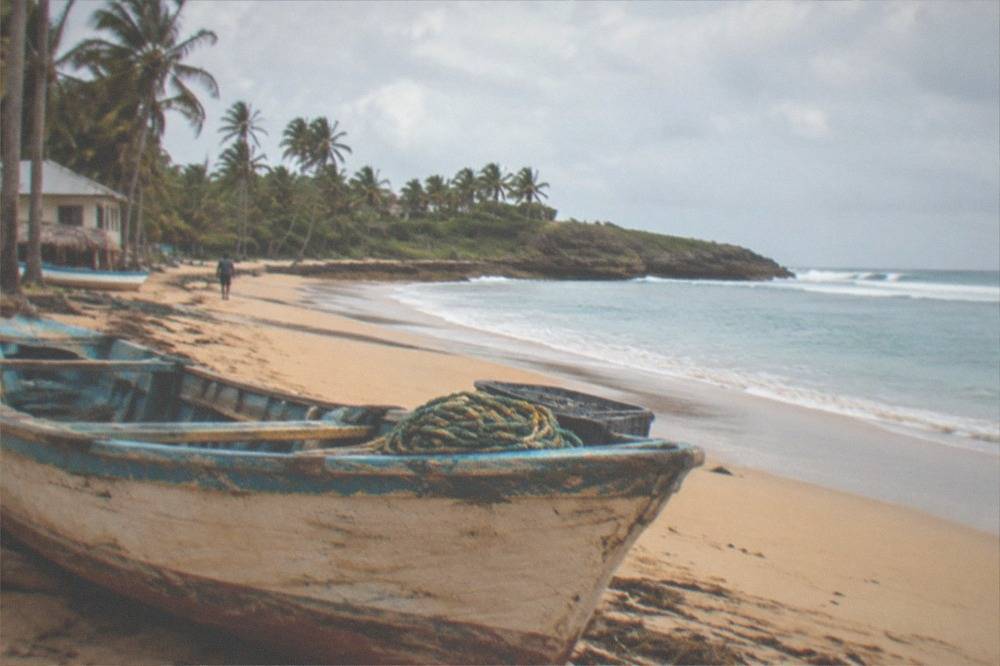 Wooden fishing boat resting on golden sand beside calm shallow water
