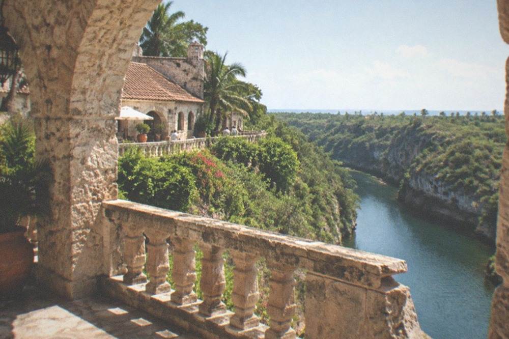 Coral stone archway and terrace overlooking a river gorge with tropical vegetation