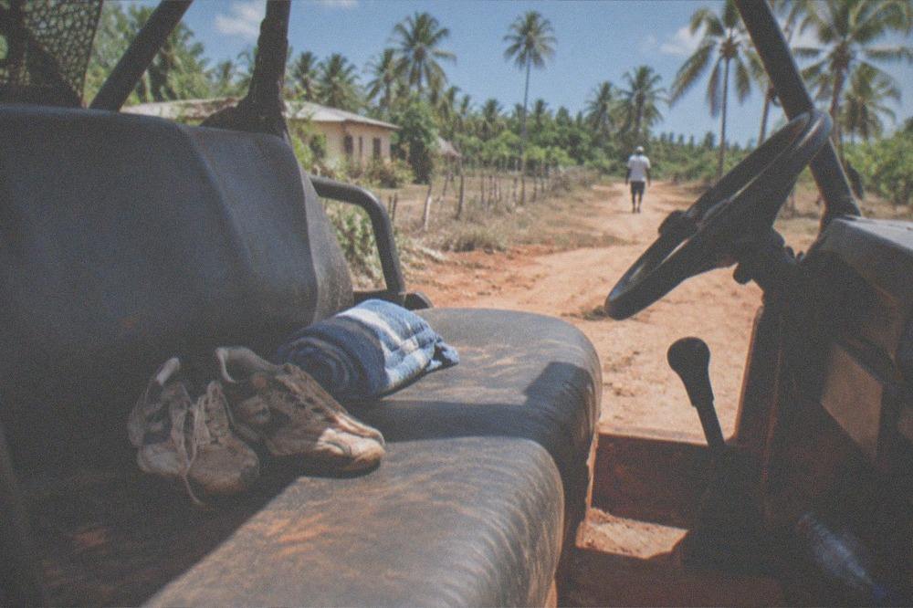 Pair of worn sneakers and a rolled towel resting on a dusty vehicle seat
