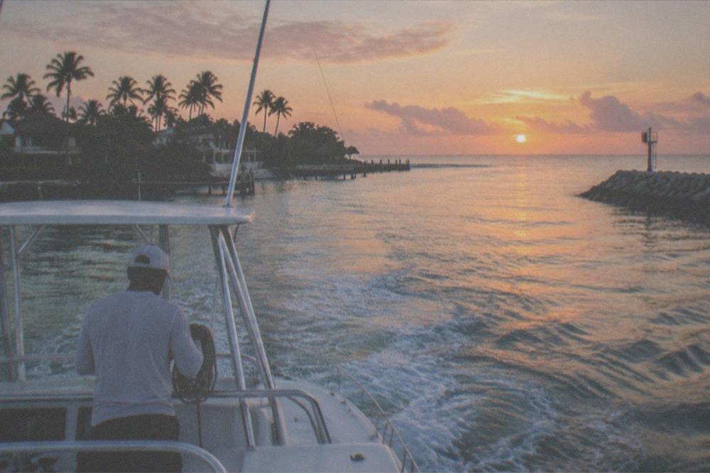 Charter boat cruising out toward open water in early morning light