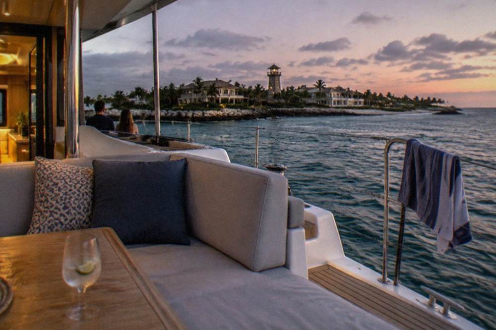 Private catamaran deck with seating and a drink table at dusk