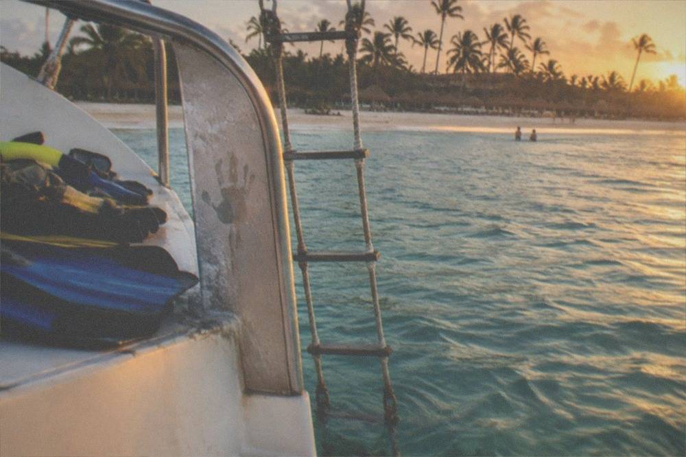 Snorkel gear and a rope ladder beside clear water at a catamaran stern