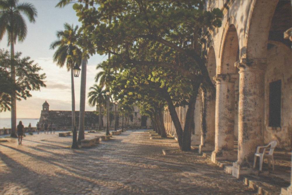 Sunlit plaza with colonial architecture and tropical trees
