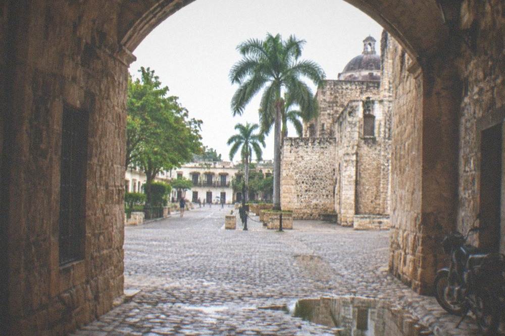 Stone archway and cobblestone lane in a colonial plaza